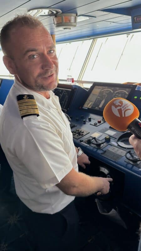 Kapitän Adrian Firsov mit Mikrofon vom Deutschen Reiseradio vor dem Gesicht