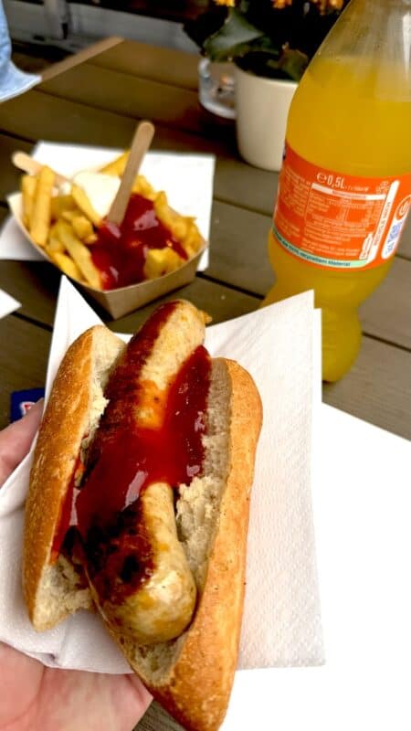 Aktionsbratwurst mit Chili und Käse, Pommes und Fanta im Hintergrund, beim Frankenlümmel auf dem Würzburger Marktplatz